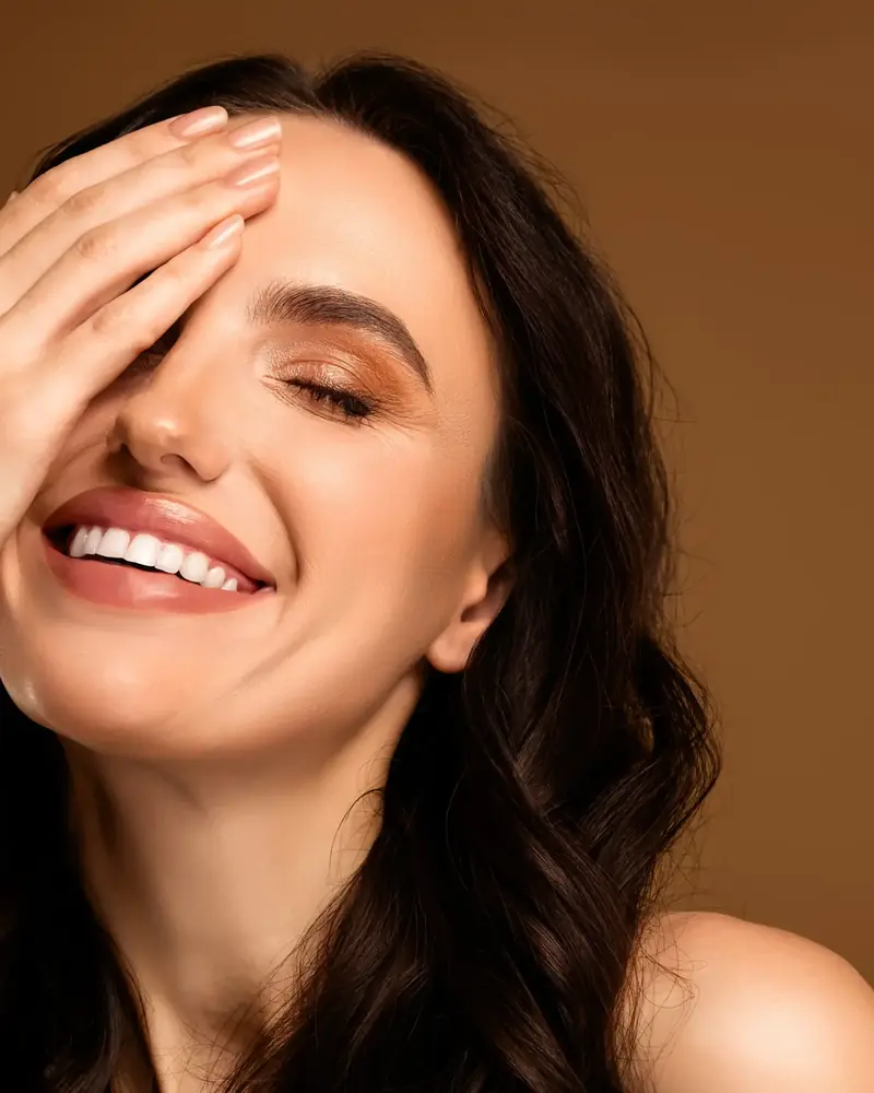 Smiling woman with natural, glowing skin against a warm background